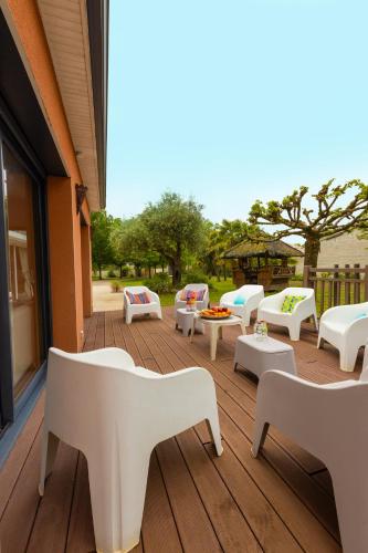 a patio with white chairs and tables on a deck at Villa-des-eaux Claires in Puymoyen