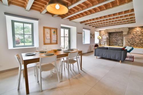 une salle à manger avec une table, des chaises et un canapé dans l'établissement Ancienne Forge avec son jardin à 2 pas de la plage, à Erdeven