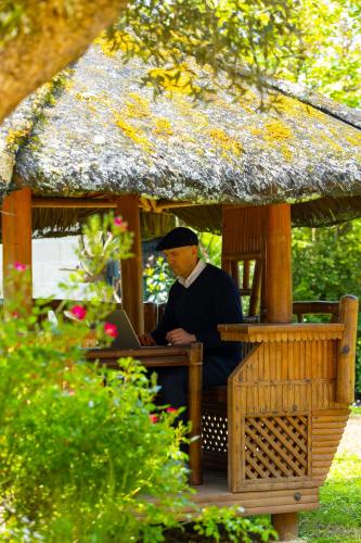 a man sitting in a gazebo with a laptop at Villa-des-eaux Claires in Puymoyen