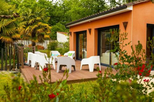 a deck with white chairs and tables on a house at Villa-des-eaux Claires in Puymoyen