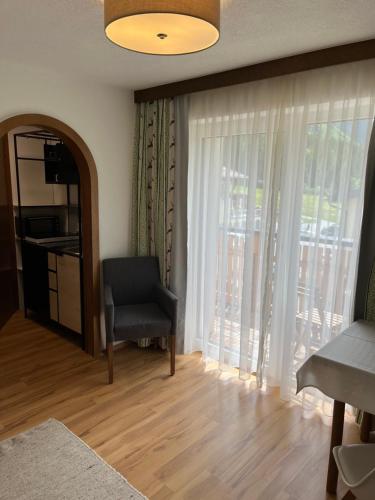 a living room with a chair and a large window at Pension Anna in Sankt Leonhard im Pitztal