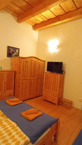 a bedroom with a bed and a tv and wooden cabinets at Kék Mátra Vendégház in Matraszentistvan