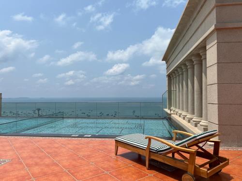 a swimming pool with a bench next to the ocean at Oscar Seaview Apartment in Phu Quoc