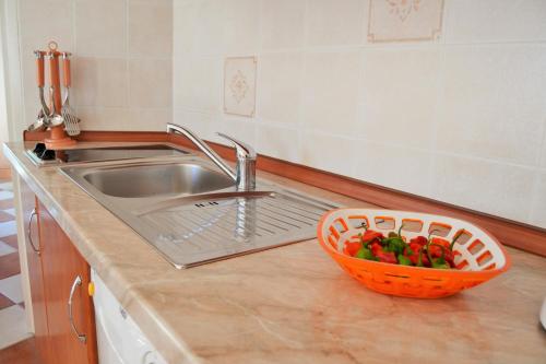 a kitchen counter with a sink and a basket of peppers at Apartments Green Village in Premantura
