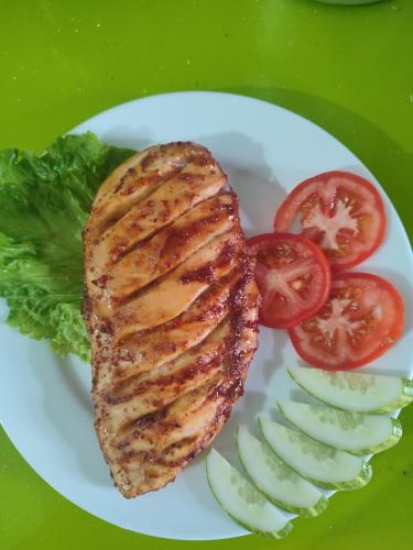 un pezzo di carne su un piatto con pomodori e cetrioli di Tam Coc Lights Hotel a Ninh Binh