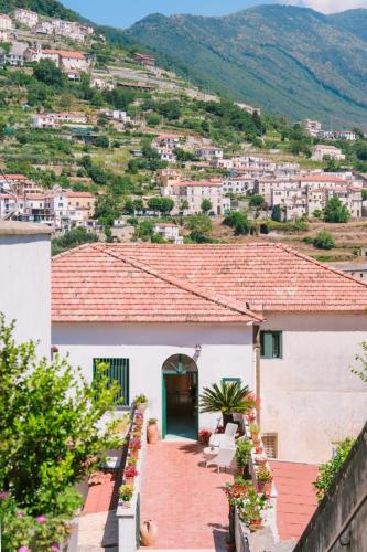 a white house with a red roof with a blue door at Berardino Holiday House in Ravello