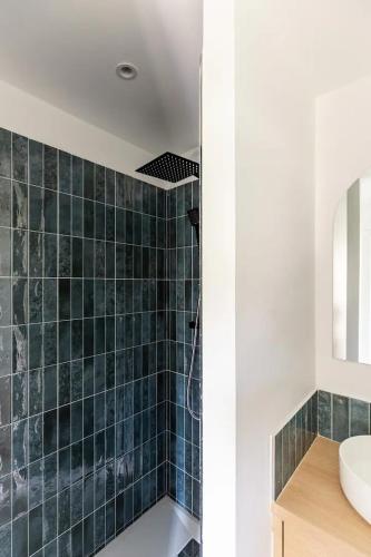 La salle de bains est pourvue d'un lavabo et d'un mur carrelé vert. dans l'établissement Charmant appartement calme proche de Paris, à Saint-Denis