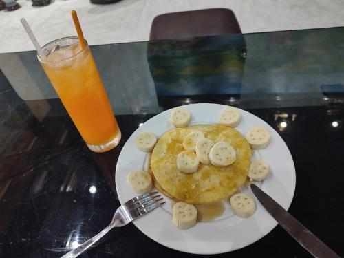 un piatto di pancake con sopra delle banane con una forchetta e una bevanda di Tam Coc Lights Hotel a Ninh Binh