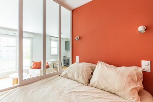 a bed in a room with an orange wall at Appartement cosy avec terrasse proche de Paris in Saint-Denis