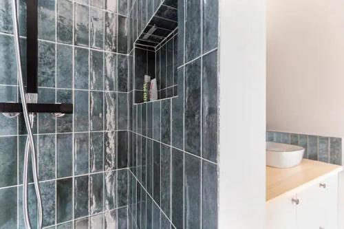 a bathroom with a shower with black tiles at Appartement cosy avec terrasse proche de Paris in Saint-Denis