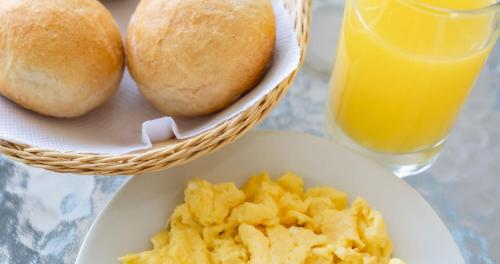 a plate of food with bread and a basket of orange juice at Hostal Los Frayles in Paracas