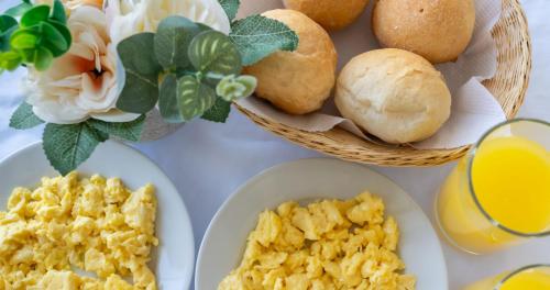 a table with eggs and bread and a glass of orange juice at Hostal Los Frayles in Paracas