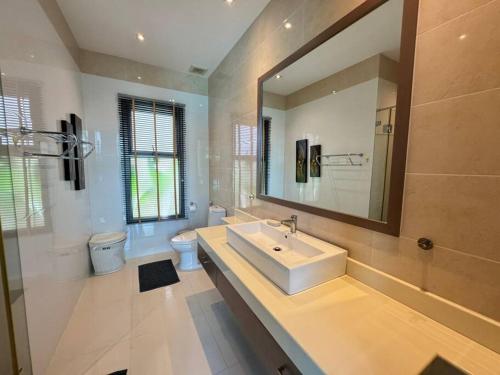 une salle de bain avec un lavabo et un miroir et des toilettes dans l'établissement Aromdee 2 Villa by G Estate Phuket, à Ban Saiyuan (1)