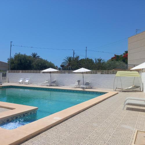 a swimming pool with chairs and umbrellas at Habitalento in El Campello