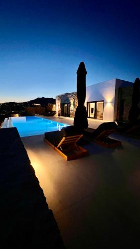 a person sitting on a patio near a swimming pool at Villa Taiyo Mykonos in Mikonos