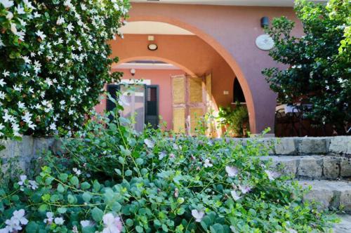 een huis met een boogvormige deuropening en een tuin met bloemen bij Villa Carola in Gallipoli