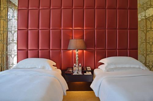 two beds in a room with a red wall at Mandarin Oriental Al Faisaliah, Riyadh in Riyadh