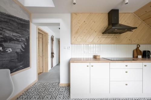 a kitchen with white cabinets and a black hood at MiLove in Milówka