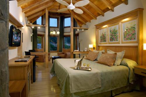 1 dormitorio con 1 cama y ventilador de techo en Hotel y Cabañas Le Village en San Martín de los Andes