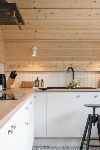 a kitchen with white cabinets and a wooden ceiling at MiLove in Milówka