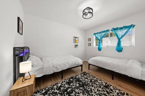 two beds in a room with blue curtains and a rug at The Cozy Haven Retreat in Novato