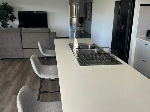 a kitchen with a counter with a sink and chairs at The Nagambie Stay in Nagambie