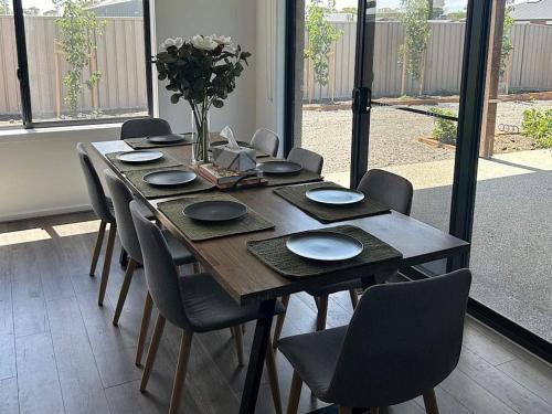 a wooden table with chairs and a vase of flowers at The Nagambie Stay in Nagambie