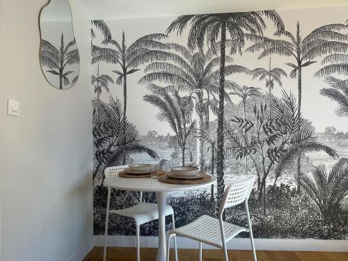 une salle à manger avec une table avec du papier peint de palmiers dans l'établissement LeRelaisdOdile - Appart Cosy au Vieux-Lille, à Lille