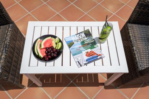 a table with a bowl of fruit and a book and a drink at Avra Milos in Zefiría
