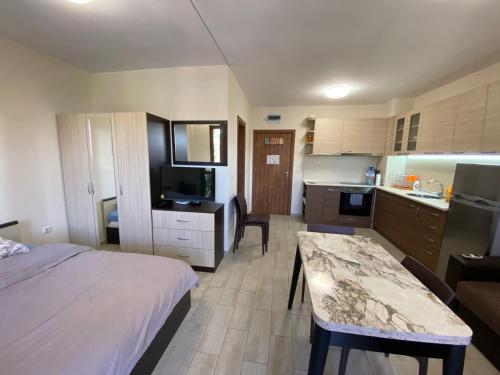 a bedroom with a bed and a kitchen with a table at КАСКАДАС Луксозни нови студия in Sunny Beach