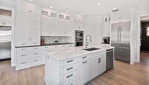 una cocina blanca con armarios blancos y electrodomésticos de acero inoxidable en Blue Jasmine, en Marco Island