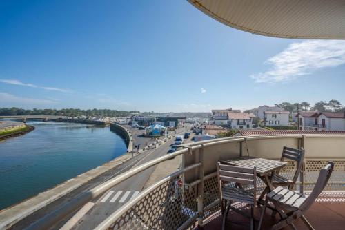 a balcony with a table and chairs overlooking a river at Hôtel Océan in Capbreton