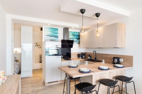 une cuisine avec un îlot doté de chaises et d'un comptoir dans l'établissement Studio luxe vue panoramique baie La Baule, à La Baule