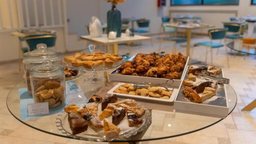 a table with several trays of desserts and pastries at Hotel Eden in Toscolano Maderno