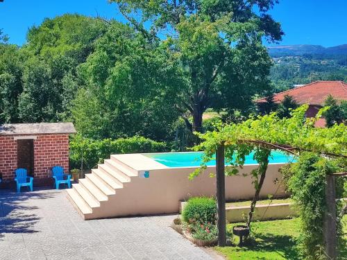 a swimming pool in a garden with blue chairs at Casa do Avô Manuel in Valença
