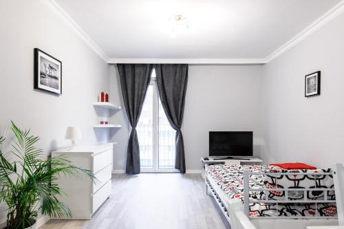 Habitación blanca con cama y TV en Apartament Grójecka Korotyńskiego en Varsovia