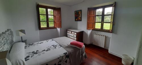 a bedroom with a bed and a dresser and two windows at La Sierra del Aguanaz in Entrambasaguas