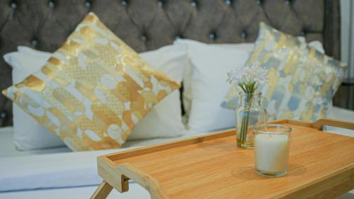 a wooden table with a glass of milk and flowers on a bed at Eaton Residence KLCC - KL SUITE in Kuala Lumpur