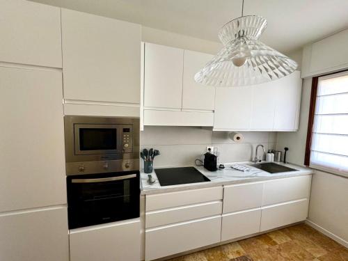 a kitchen with white cabinets and a microwave at Appartamento alle Terrazze in Venice-Lido