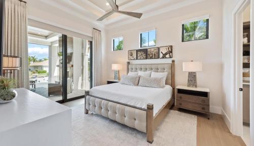 ein weißes Schlafzimmer mit einem Bett und einem Tisch in der Unterkunft Quintara Luxe in Marco Island