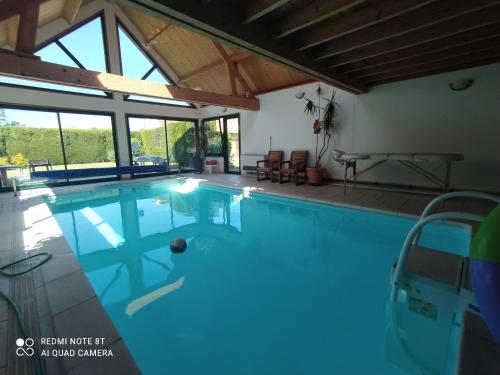 a swimming pool in a house with a large window at Au Nid d'Amour in Clarques