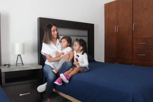 a woman and two children sitting on a bed at Suites Independencia Oaxaca in Oaxaca City