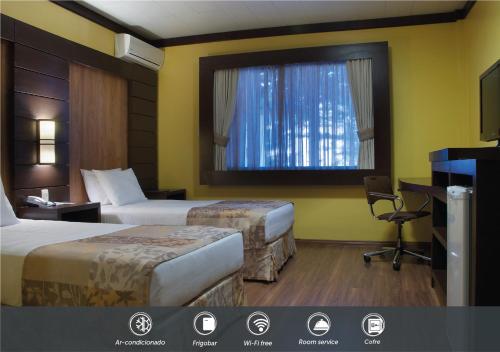 a hotel room with two beds and a window at Master Gramado Hotel - Espaço Kids Incrível in Gramado