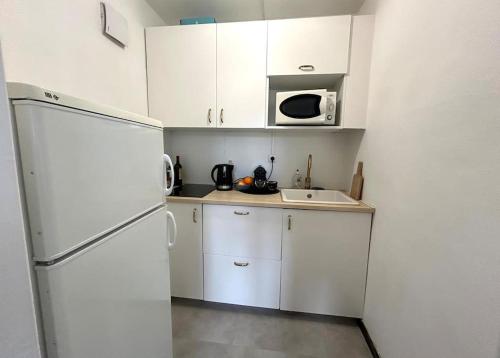 La cuisine blanche est équipée d'un réfrigérateur et d'un évier. dans l'établissement David - T2 5 mn gare TGV et Grand Palais, à Lille