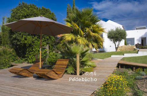 two chairs and an umbrella on a wooden deck at Pédebicho Serra da Arrábida Country Inn and Studios in Azeitao