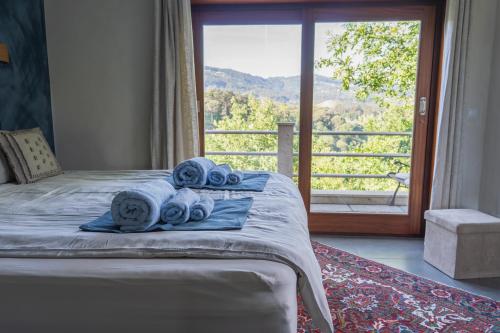 a bedroom with a bed with towels and a large window at Travessia do Sol - Eco Lodge and Retreat Centre in Gemieira