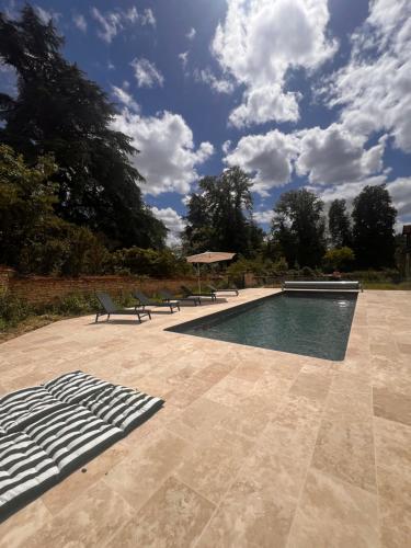 une piscine avec deux bancs et un bleu dans l'établissement Le Relais en Berry, à Montierchaume