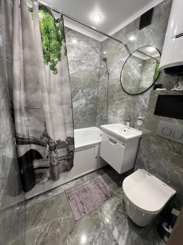 a bathroom with a shower curtain and a toilet and a sink at Гоголя 41 in Karagandy