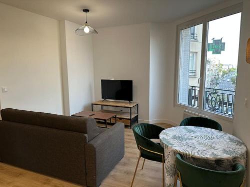 ein Wohnzimmer mit Sofa und Fernseher in der Unterkunft Appartement Moderne in Gennevilliers
