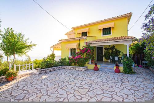 a yellow house with a patio in front of it at Caza Levantiera in Kalamitsi